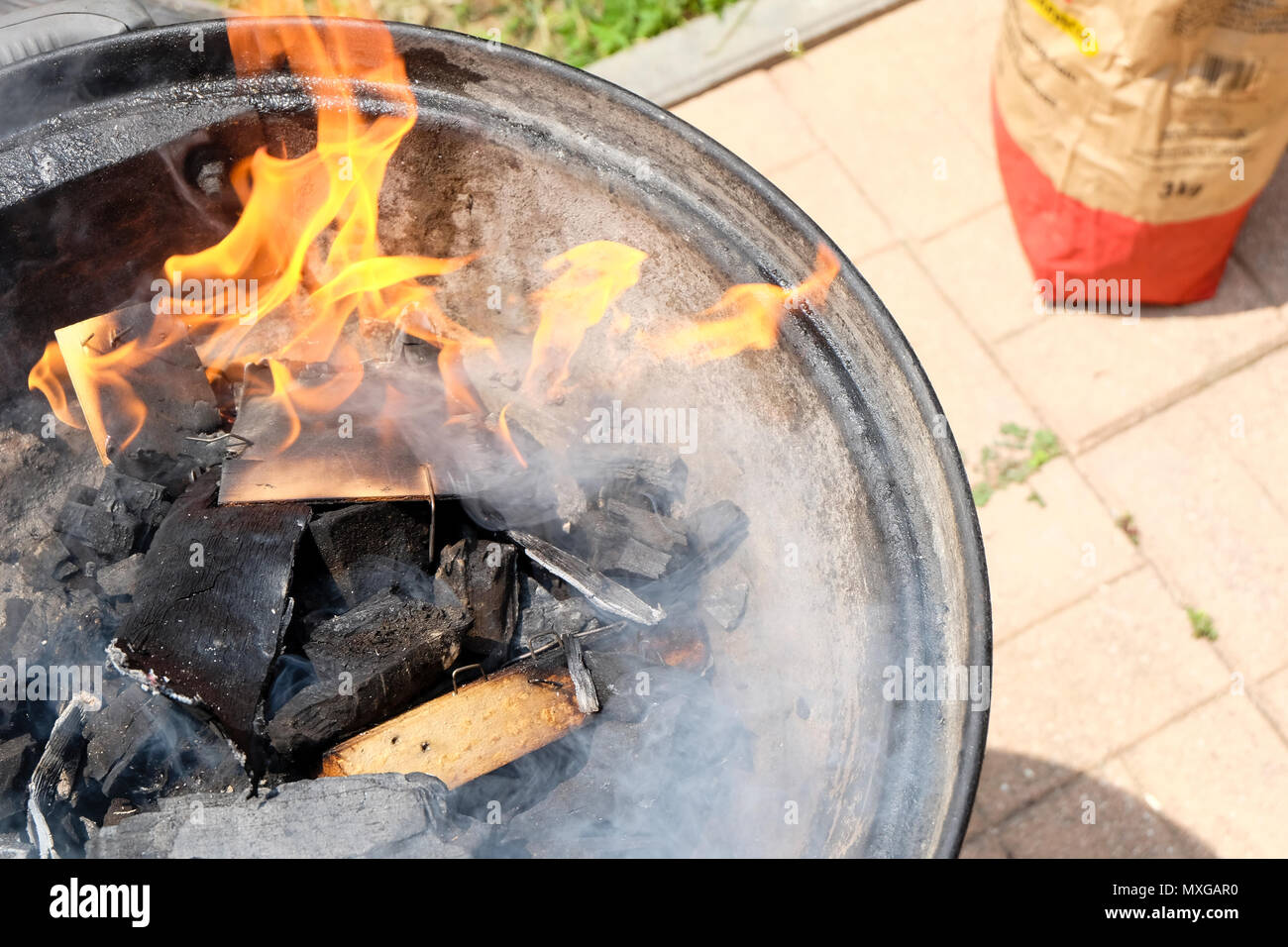 Una giornata di sole in giardino, iniziando il fuoco nel grill e poi cuocere carne con gli amici Foto Stock
