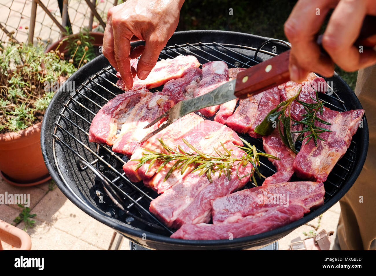 Una giornata di sole in giardino, iniziando il fuoco nel grill e poi cuocere carne con gli amici Foto Stock