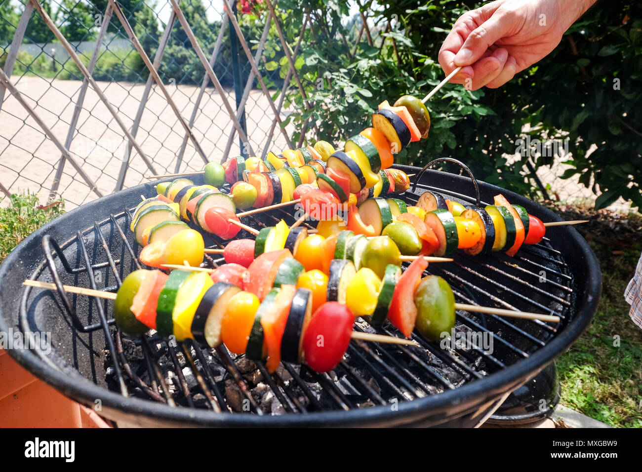 Per la cottura e Grill verdure - zucchine e pomodoro pepeer - gli spiedini su un barbecue all'aperto di un soleggiato weekend rilassante Foto Stock