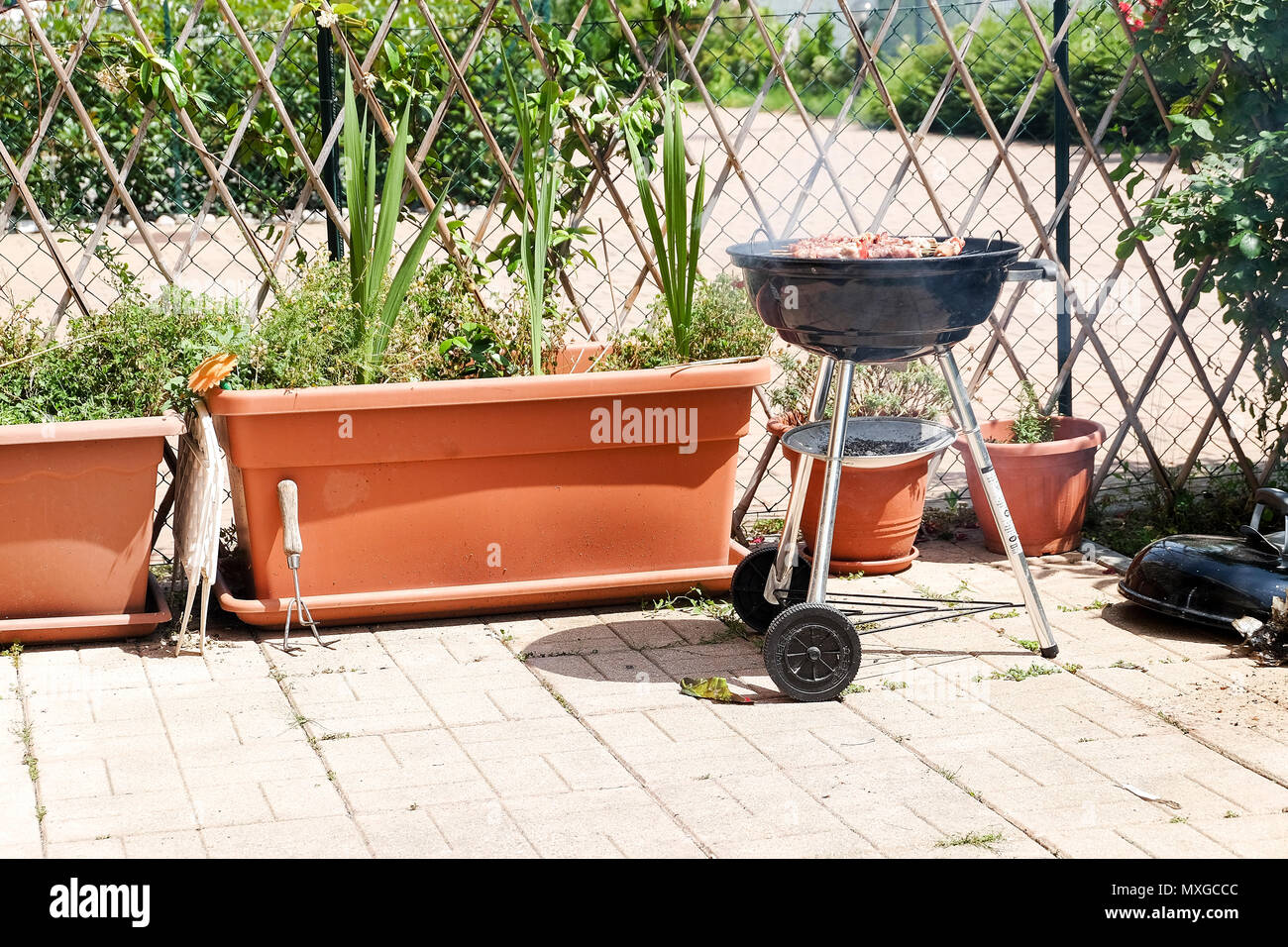 Una giornata di sole in giardino, iniziando il fuoco nel grill e poi cuocere carne con gli amici Foto Stock