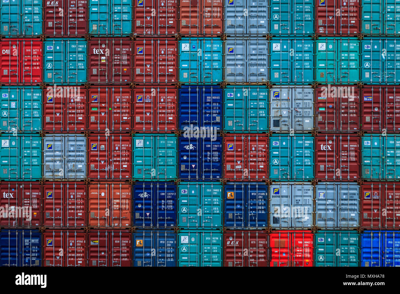 Contenuti. Vuoti accatastati storagecontainers spedizione mai così colorati come attendono ri utilizzando presso il locale terminale marittimo. Foto Stock