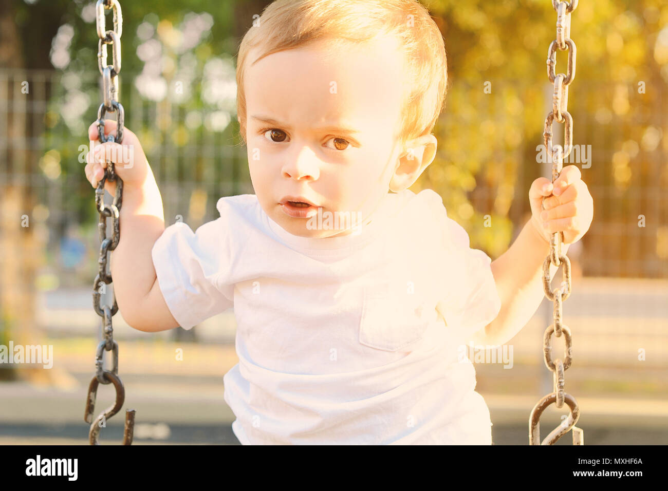 Carino baby boy divertirsi su altalena in un parco. Foto Stock