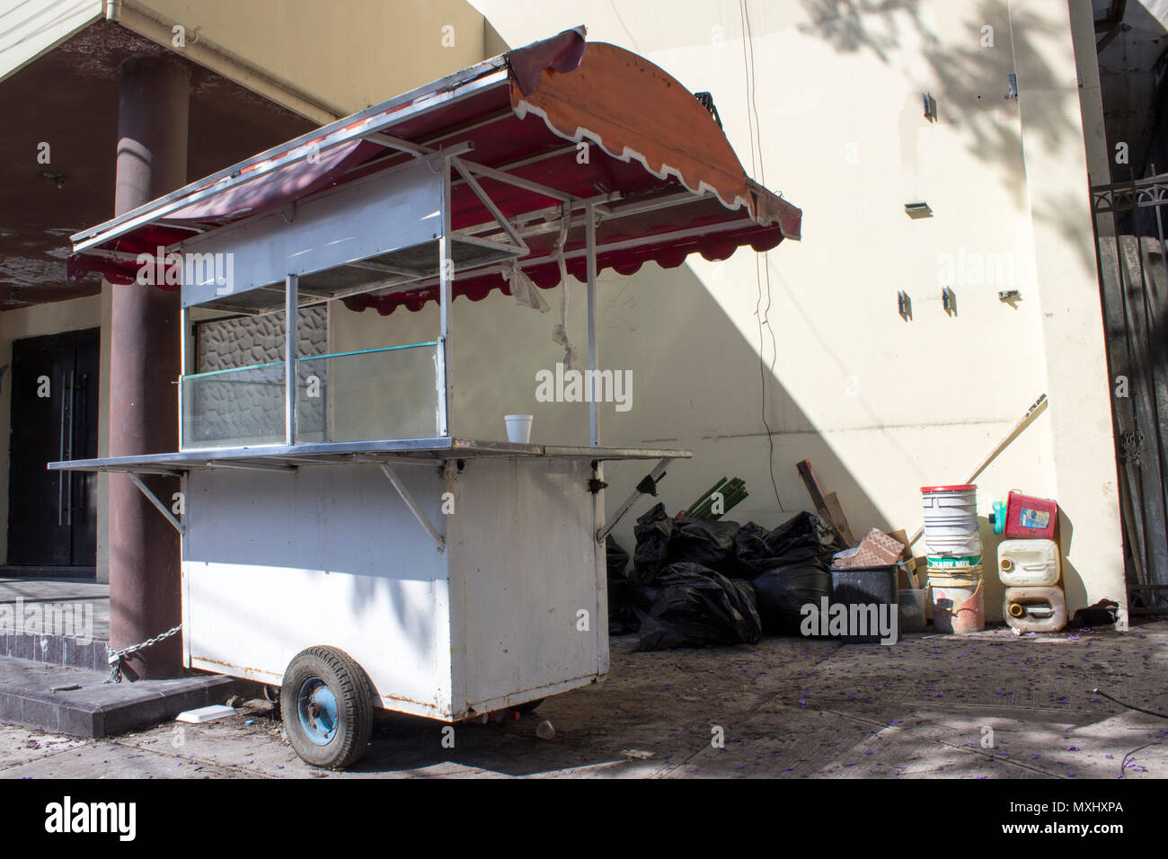 Abbandonato food cart concatenati a un edificio abbandonato. A lato, cestino nero borse e contenitori vuoti. Foto Stock
