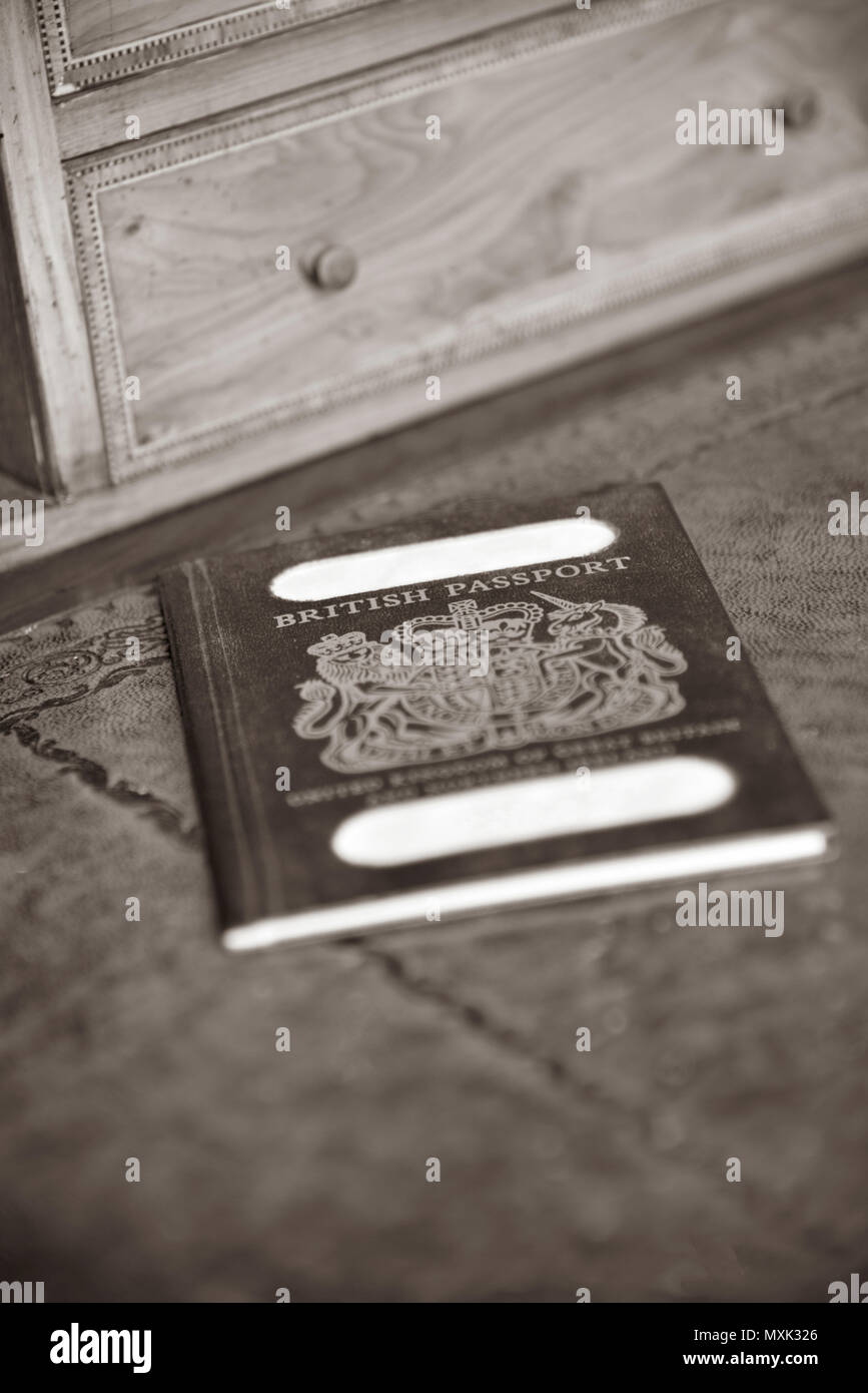 Blu passaporto britannico su antiche scrivania in legno con nome tranciati in seppia con profondità di campo ridotta Foto Stock
