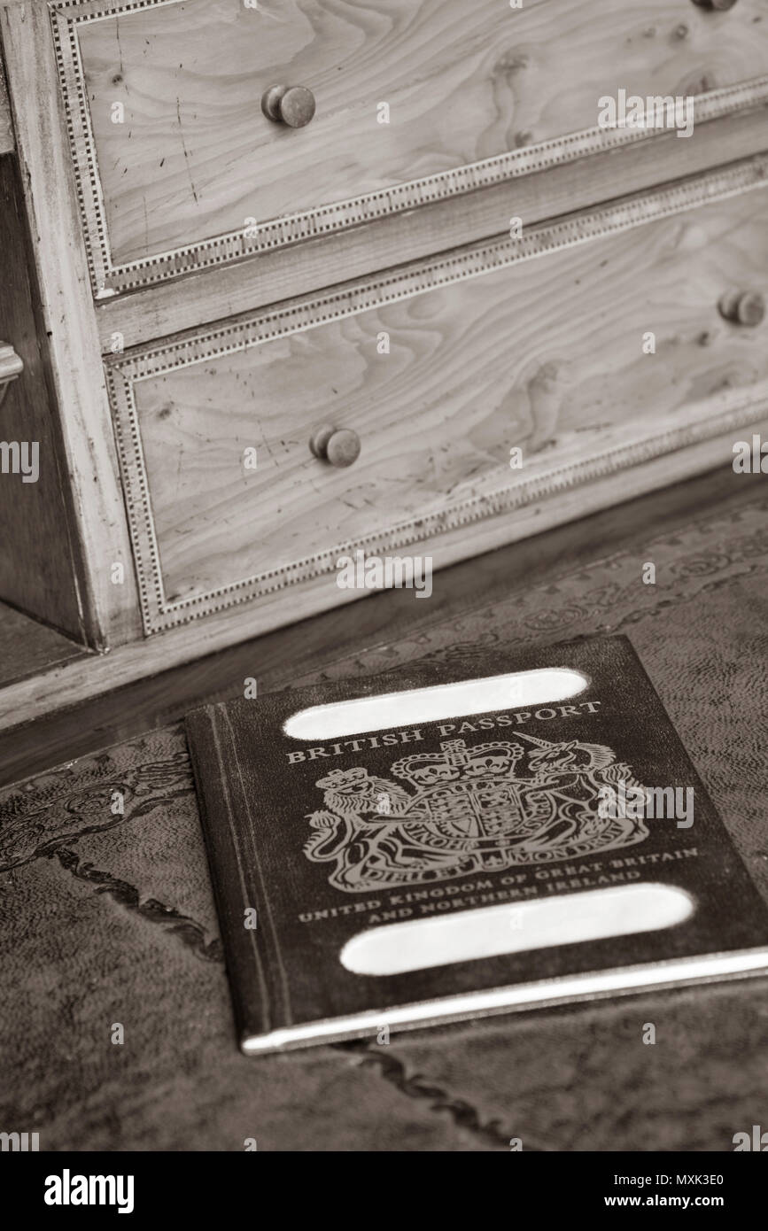 Blu passaporto britannico su antiche, tutti in focus scrivania in legno con nome tranciati in seppia, tutti in focus Foto Stock