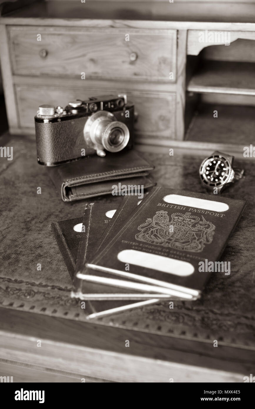 Antica scrivania con passaporti, vecchio leica fotocamera, portafoglio in pelle e guardare in seppia Foto Stock