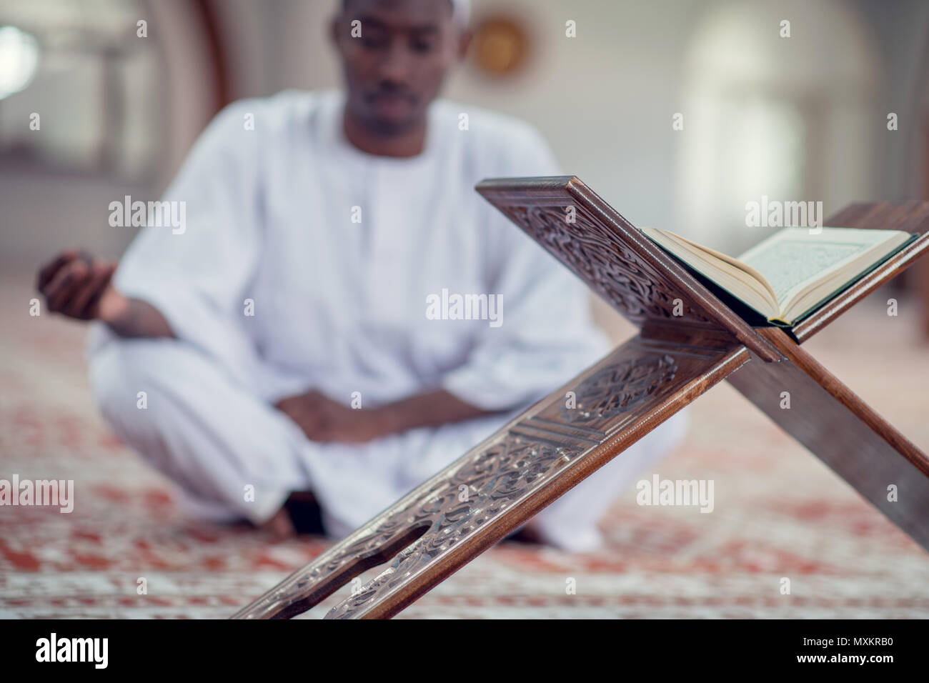Neri africani uomo musulmano è in preghiera nella moschea di aprire il libro sacro del Corano Foto Stock