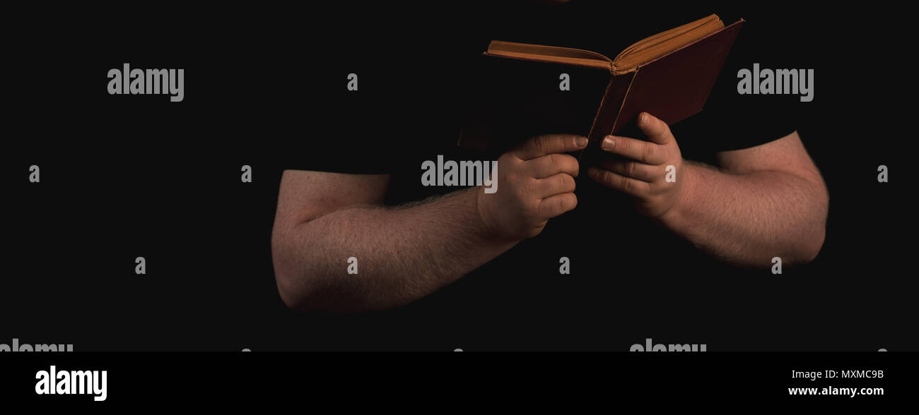 Giovane uomo la lettura di un libro contro lo sfondo scuro Foto Stock