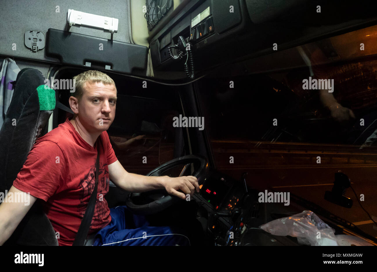 Conducente siede nella cabina di un autocarro parcheggiato di notte Foto Stock