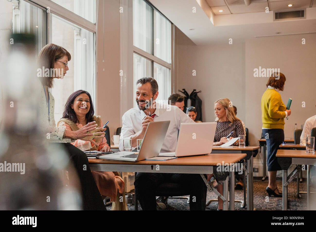 Co-lavoratori a parlare e discutere di informazioni dal computer portatili. Avendo un incontro durante un lunchbreak dalle conferenze di affari. Foto Stock