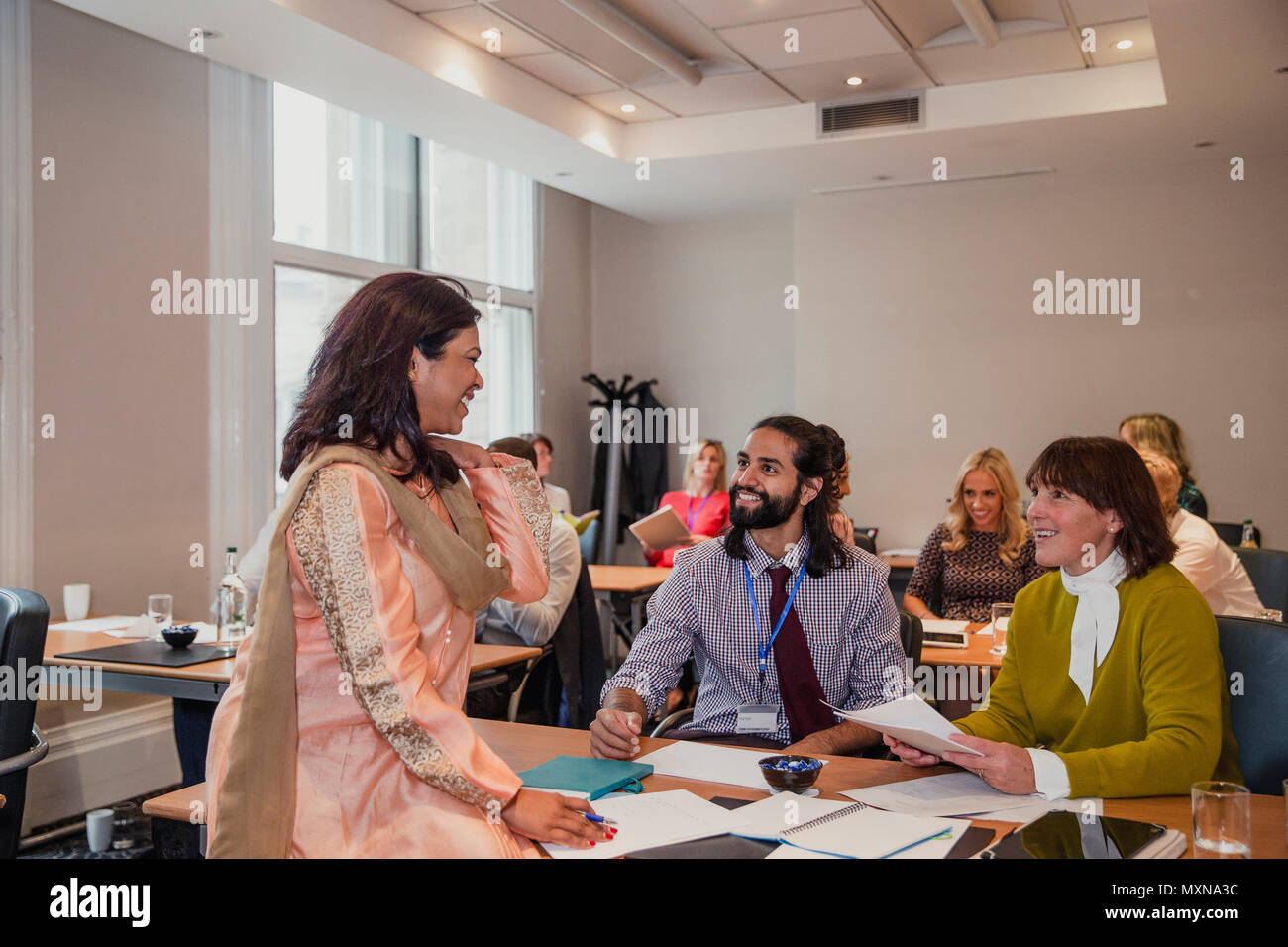 Gruppo multirazziale parlare sui loro note dopo una presentazione in occasione di una conferenza. Foto Stock