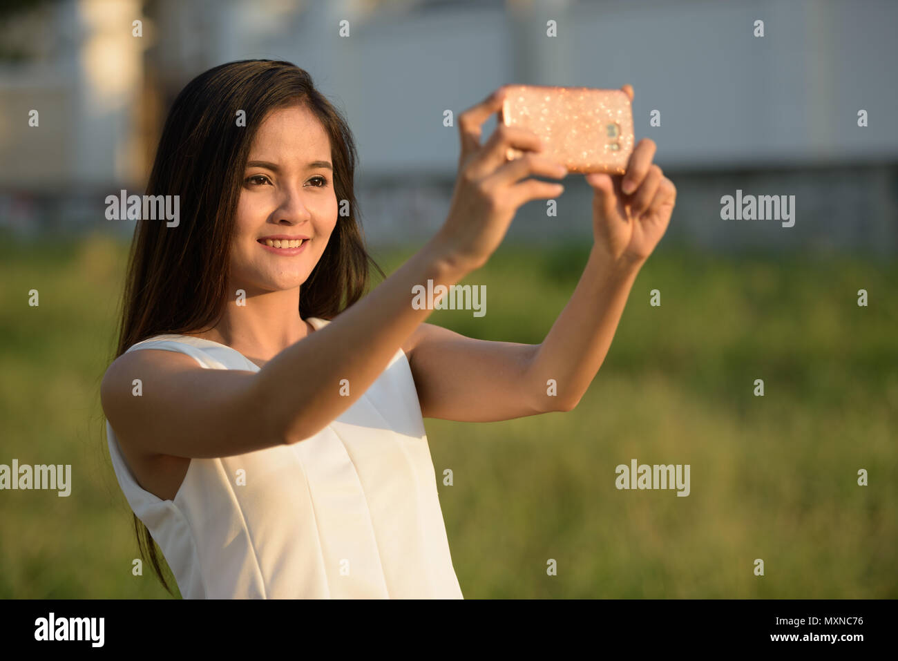 Felice giovane donna asiatica sorridere mentre prendendo selfie foto con Foto Stock