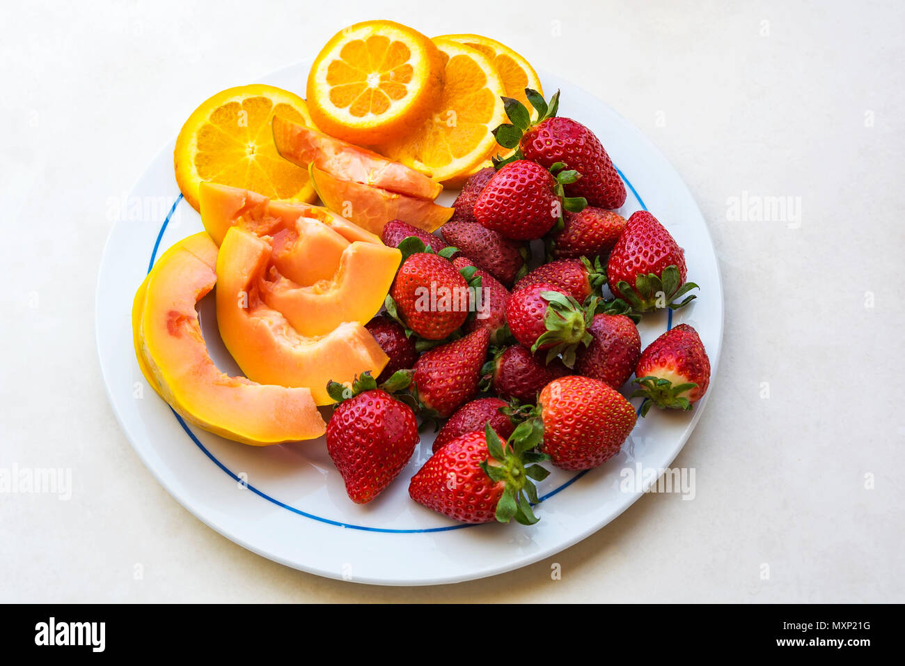 Sulla piastra sono ripe rosso Fragole, a fettine papaia e fettine di arancia, vista dall'alto Foto Stock