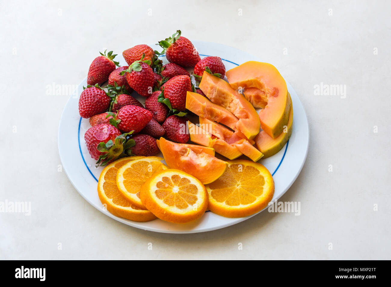 Su di una piastra sono fette di papaia fettine di arancio e rosso maturo di fragole, vista dall'alto Foto Stock