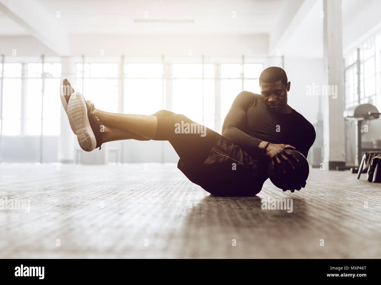 Athletic uomo addome facendo esercizio sul pavimento. L'uomo facendo crossfit allenamento tramite una palla medica presso la palestra. Foto Stock