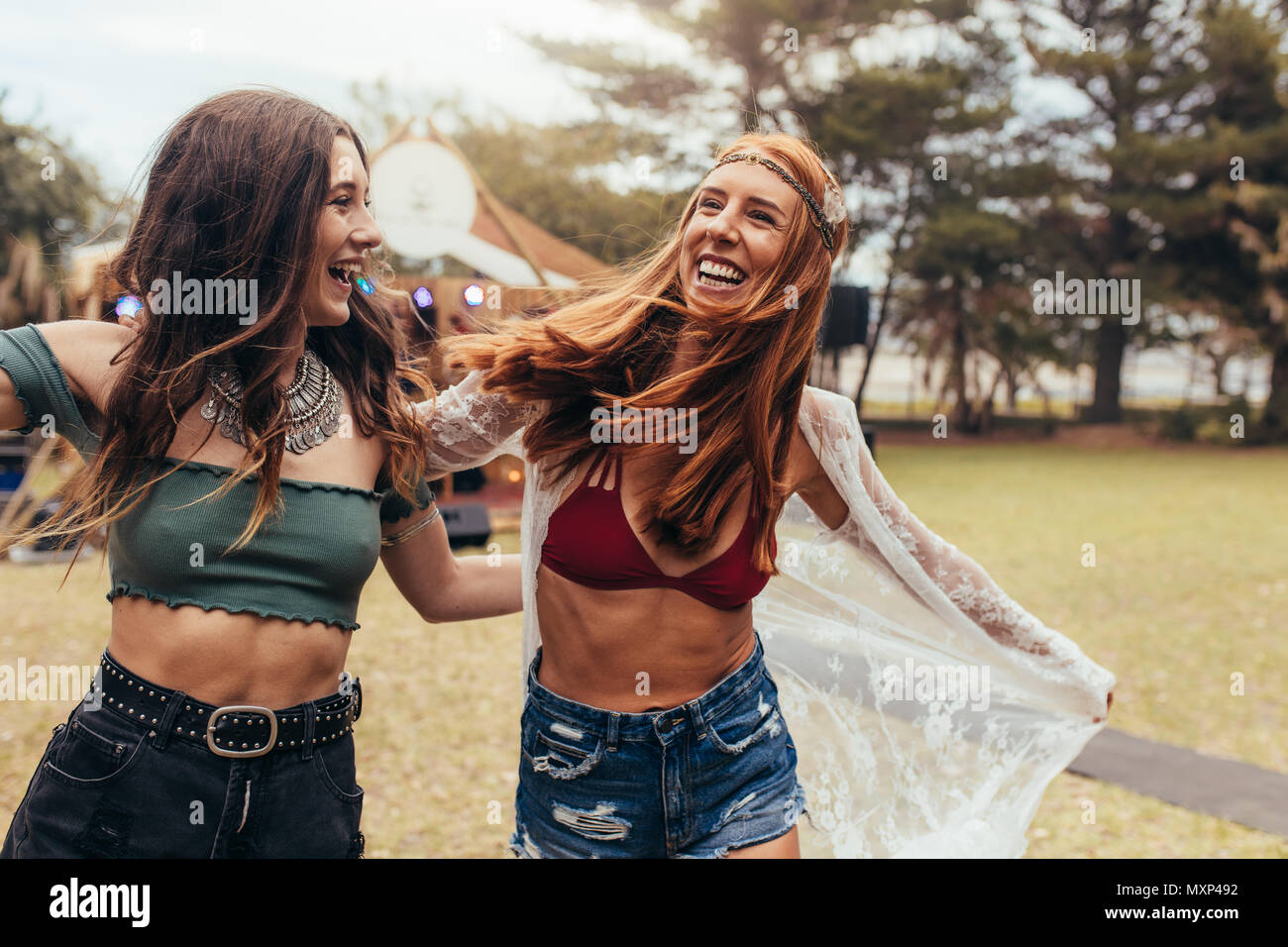 Due ragazze sorridenti e avente un grande tempo presso il festival di musica. Amiche in estate godendo di usura presso il festival di musica. Foto Stock