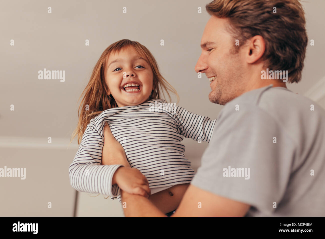 Felice padre e figlia gioca in casa. L'uomo il sollevamento della sua figlia mentre gioca in casa. Foto Stock