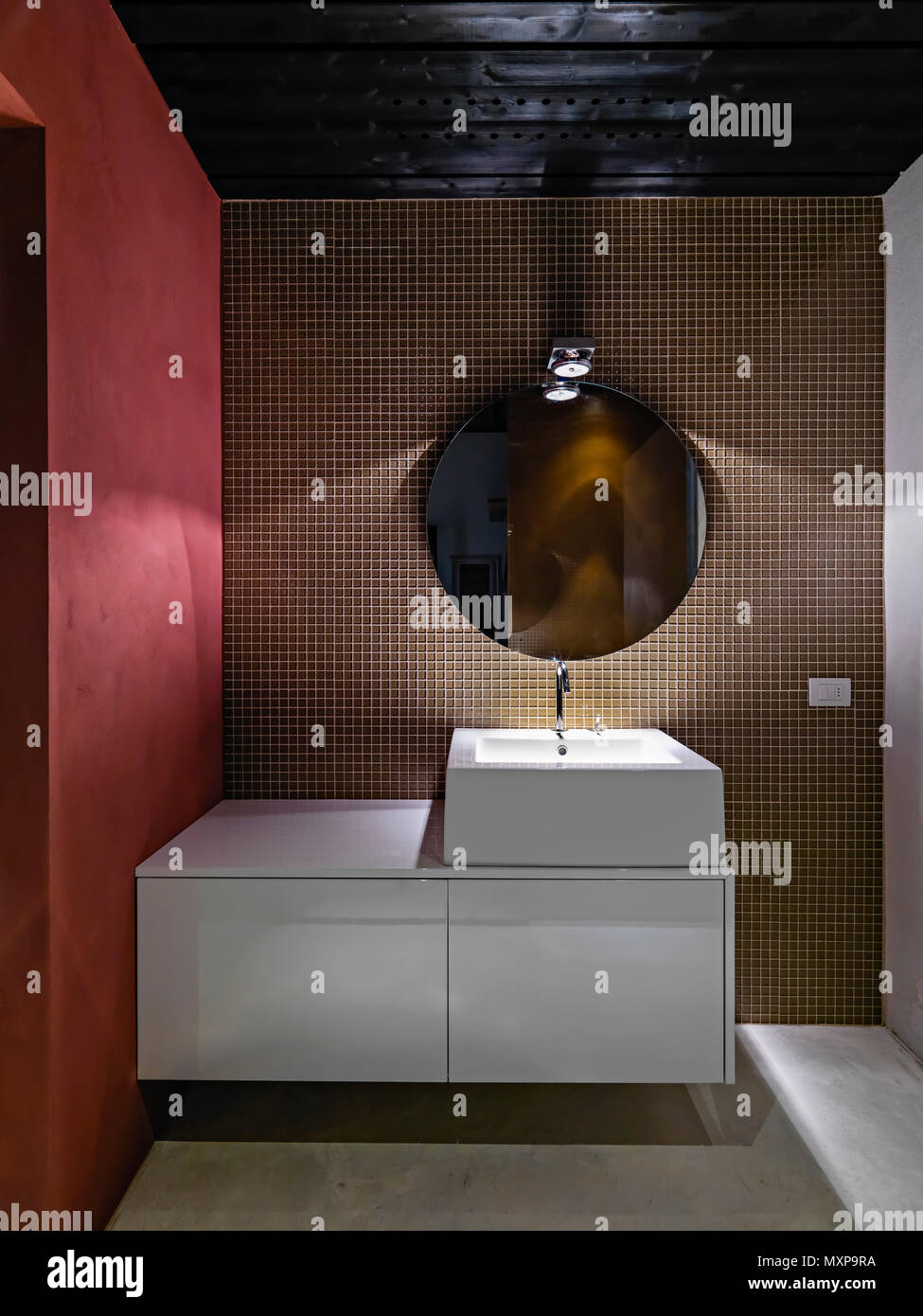 Bagno moderno interno in primo piano il dissipatore di bianco mobile con lavabo da banco la parete è ricoperta di tessere di mosaico Foto Stock