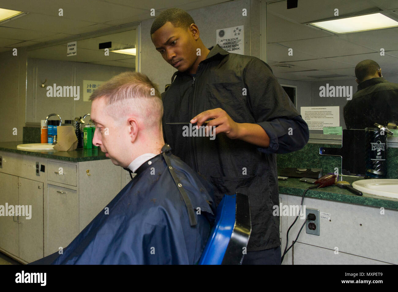 161125-N-KJ380-013 GOLFO ARABICO (nov. 25, 2016) marinaio Tevin Piper, da Augusta, Ga., dà un taglio di capelli per Sottufficiali di prima classe Christopher Coleman, dalla Eastman, Ga., in Barberia a bordo della portaerei USS Dwight D. Eisenhower CVN (69) (IKE). Ike e la sua portante Strike gruppo vengono distribuiti a supporto di funzionamento inerenti risolvere, le operazioni di sicurezza marittima e di teatro la cooperazione in materia di sicurezza gli sforzi negli Stati Uniti Quinta Flotta area di operazioni. (U.S. Foto di Marina con marinaio Neo Greene III) Foto Stock