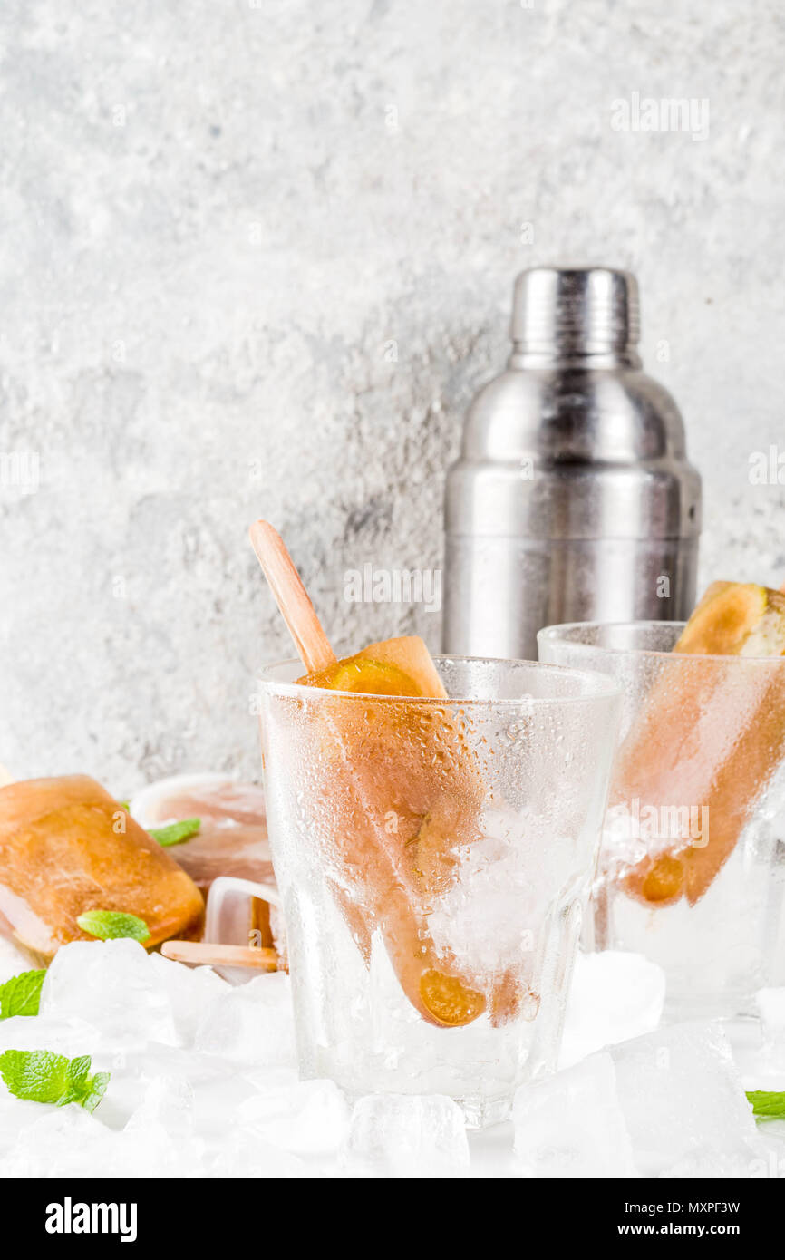 Congelati bevande rinfrescanti, cocktail estivi popsicles ricetta, cuba libre, dolce freddo il tè o il caffè con ghiaccio, lime e foglie di menta su marmo bianco backg Foto Stock