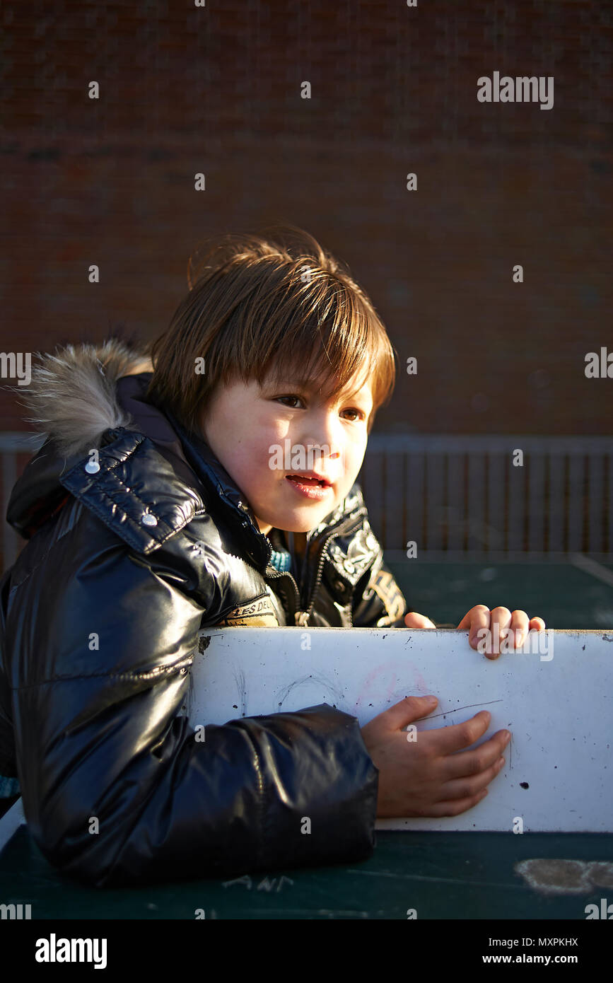 Giovane ragazzo giapponese indossa cappotto invernale giocando a scuola il parco giochi di luce del sole invernale Foto Stock
