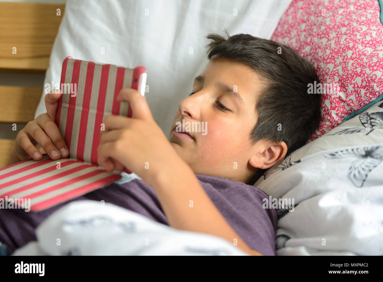 Ragazzo di 10 anni con una pastiglia a letto- messa a fuoco selettiva Foto Stock