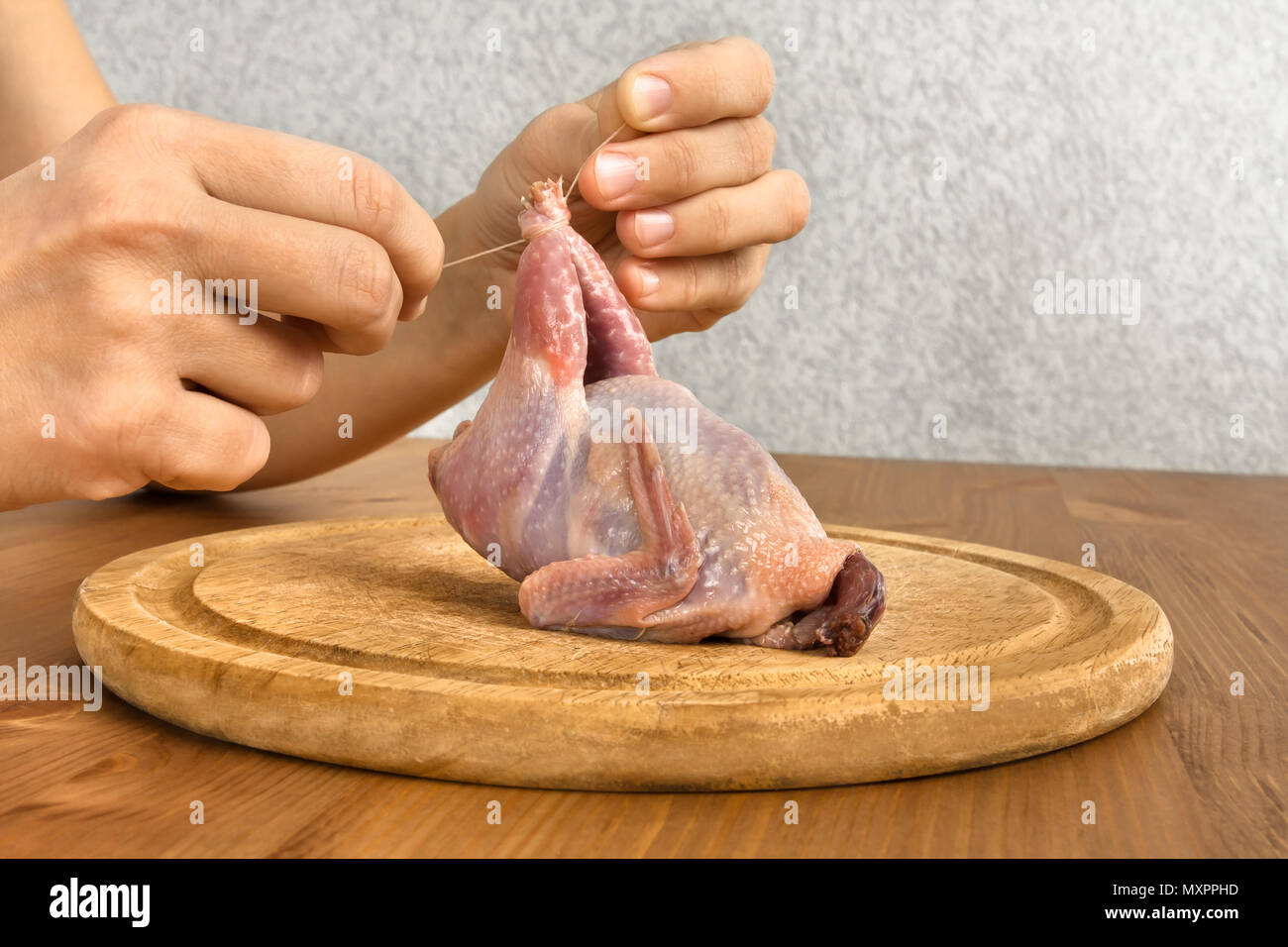 Le mani della donna la preparazione di quaglie per la cottura sul tagliere di legno Foto Stock