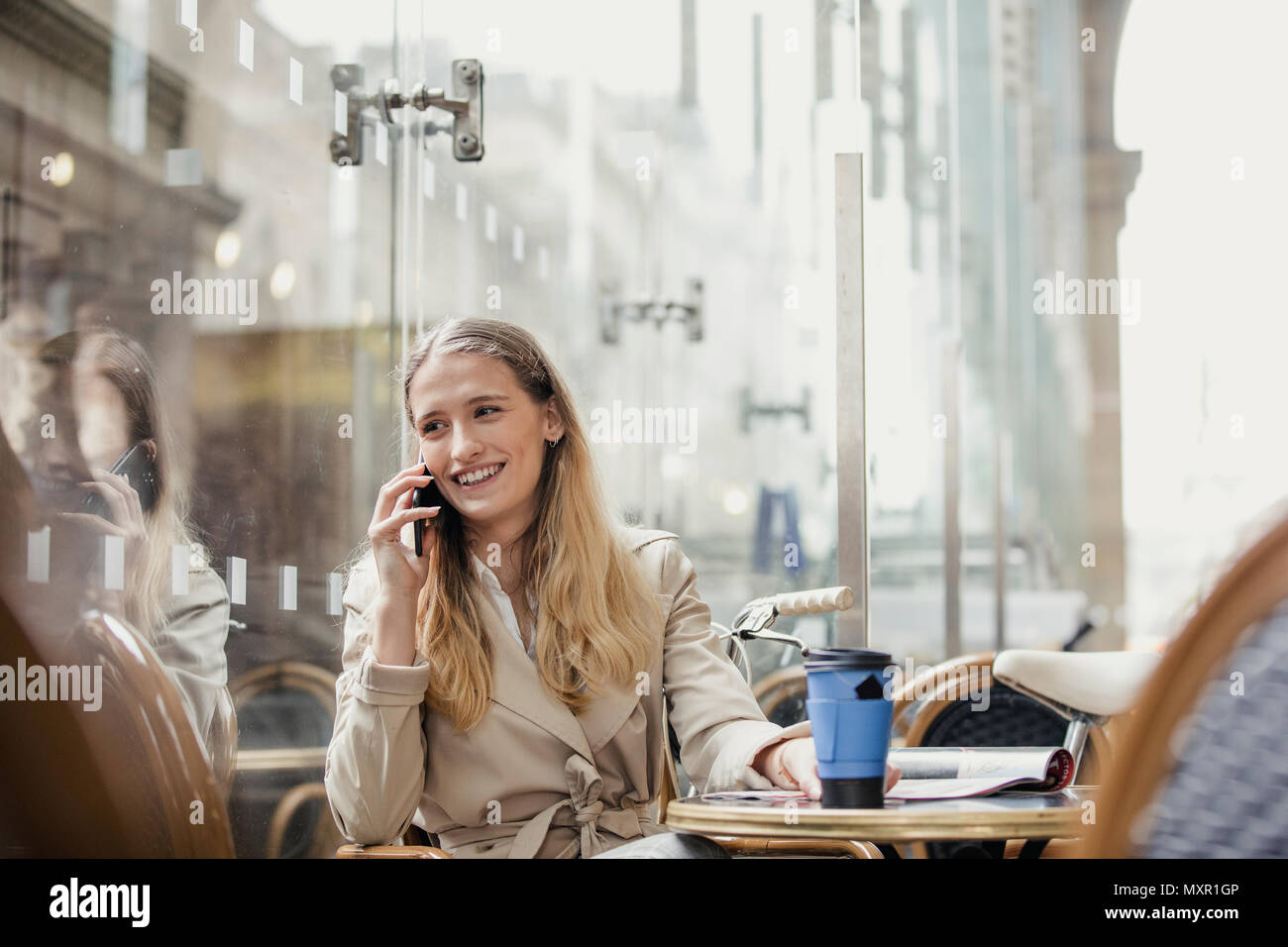 Vista frontale di un giovane adulto imprenditrice facendo una telefonata e avente un caffè prima di iniziare a lavorare. Foto Stock