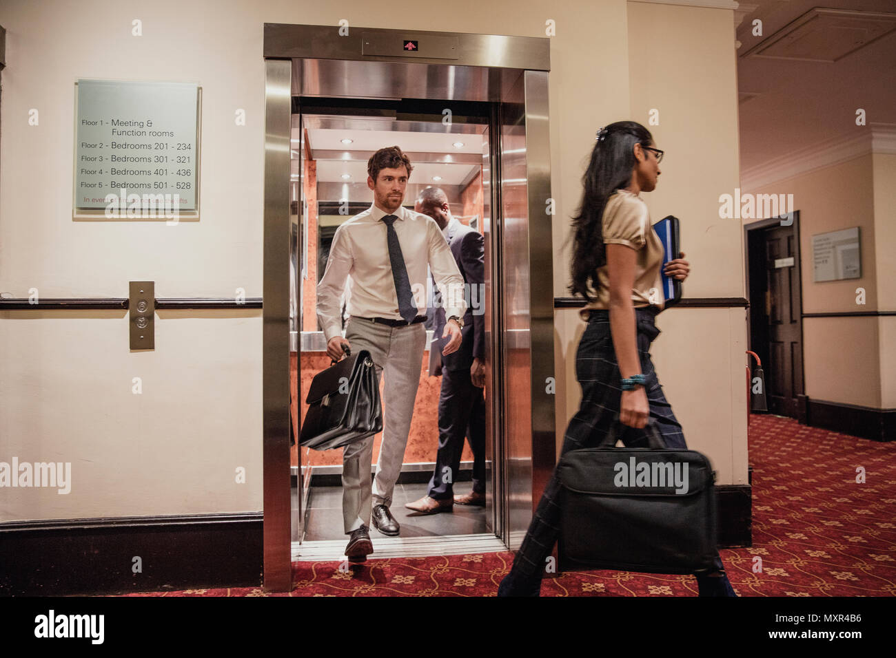 Imprenditori e imprenditrici a piedi l'ascensore in hotel dopo una riunione di affari. Foto Stock