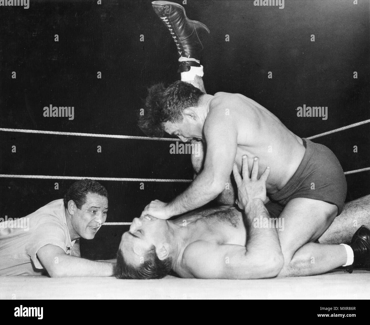 Max Baer (sinistra), ex World Heavyweight Boxing champion, arbitri una corrispondenza tra i lottatori di Primo Carnera (sul retro), sconfitti World Heavyweight Boxing champion da Baer, e Jim Londos. Chicago, IL, 5/5/1950. Foto Stock