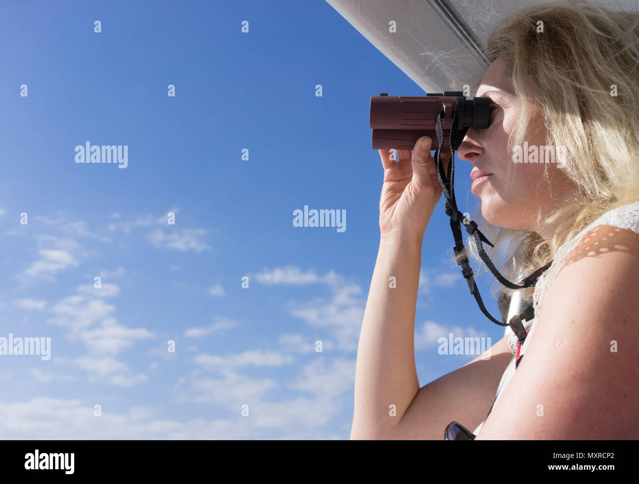 Donna che guarda il mare su una barca con il binocolo Foto Stock