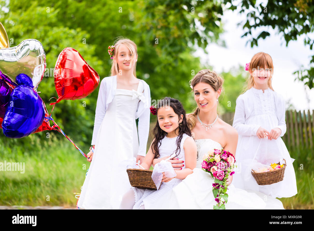 Sposa con ragazze come damigelle, fiori e palloncini Foto Stock