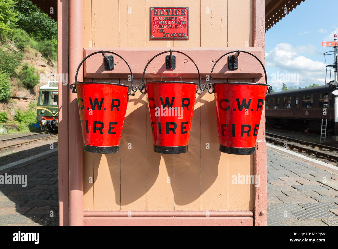 Secchi fuoco vintage Red GWR sulla piattaforma della stazione ferroviaria vintage, Severn Valley Steam Railway. Vecchie attrezzature antincendio. Foto Stock