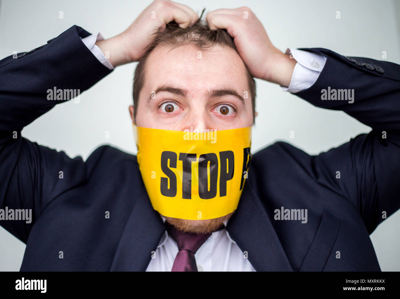 Imprenditore preoccupato e stupito per la libertà di parola violazione strappando i capelli con le mani e il nastro giallo sulla sua bocca con stop coperto. Foto Stock