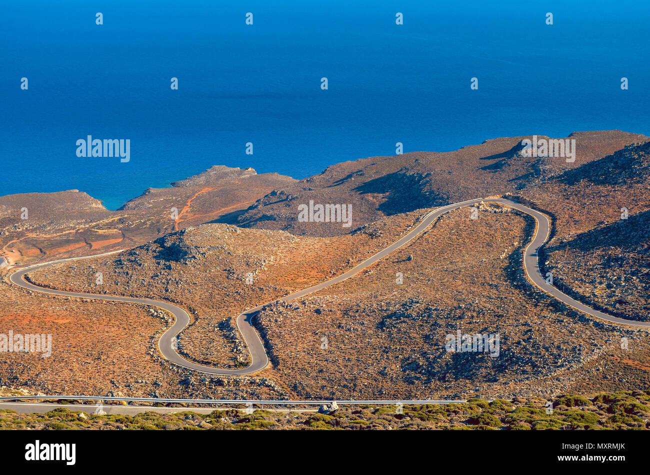 Strade strette, un sacco di giri, paesaggio secco come si guida verso il basso per coste meridionali di creta.Vista mozzafiato blu infinito del mare Libico Foto Stock