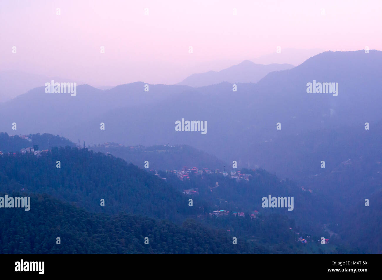Blue Hills con alberi su di essi dissolvenza in entrata la distanza e la rosa cielo incandescente di crepuscolo shot in Shimla. Vetrine la tranquillità e la bellezza del luogo Foto Stock