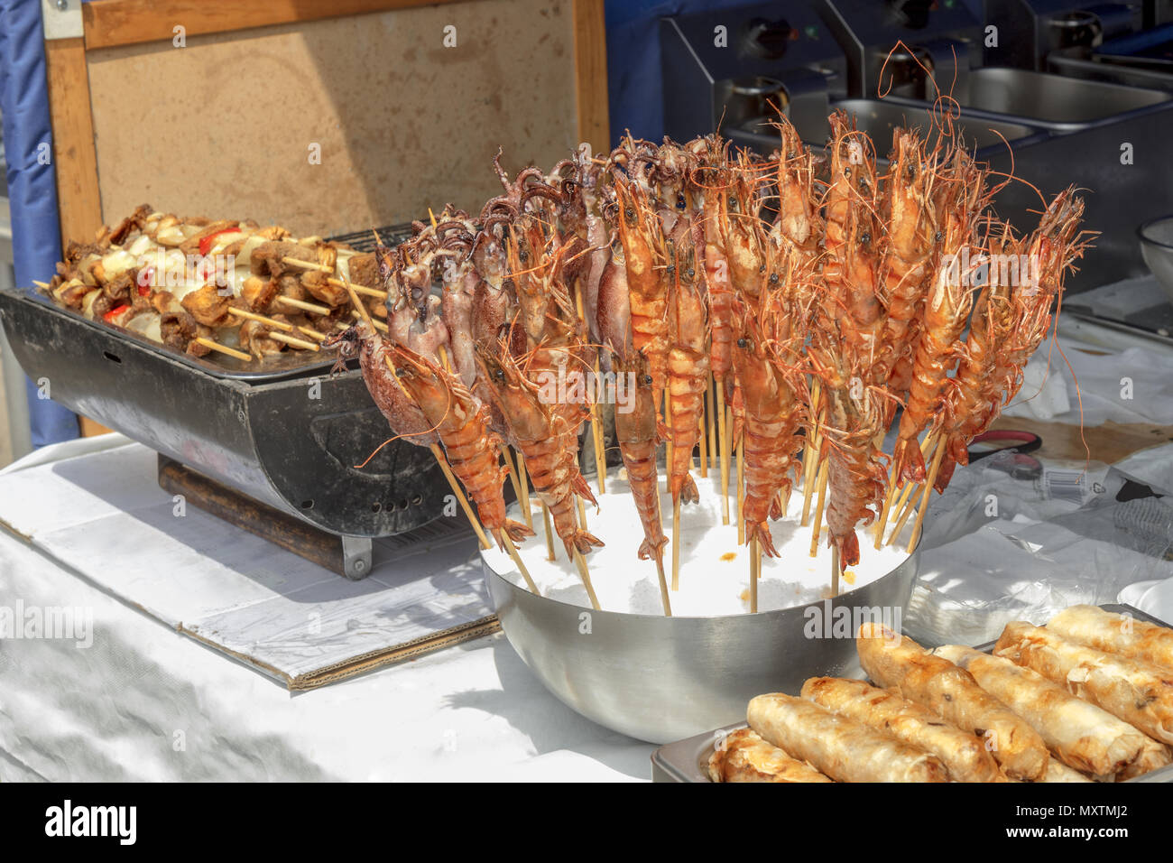 La tabella al kiosk presso Asian Street Food Festival. La strada attuale con offerta di pasto asiatici, grill con Kebab e ciotola con frutti di mare, seppia e lobste Foto Stock
