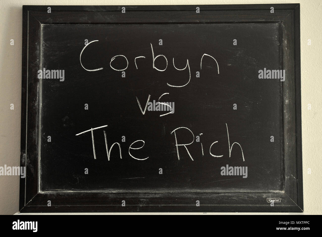 Corbyn vs il ricco in bianco gesso su una lavagna. Foto Stock