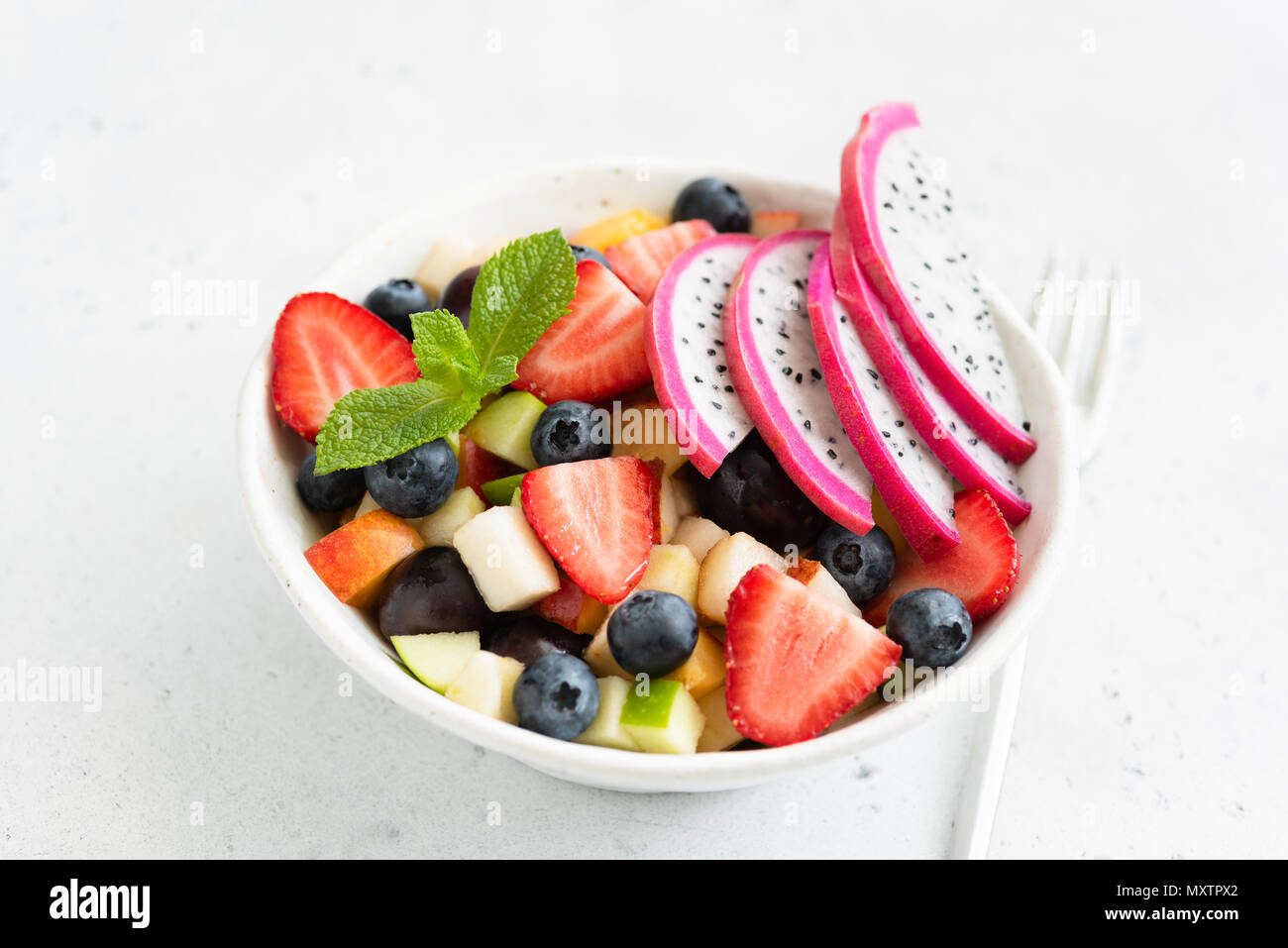 Thai insalata di frutta con pitaya e mango in una ciotola bianco, primo piano. Concetto di estate, vacanze, vegetariane e vegane dieta, mangiare sano e salute Foto Stock