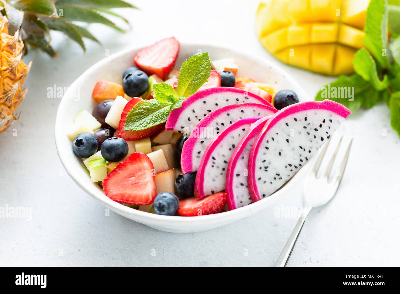 Thai insalata di frutta con pitaya e mango in una ciotola bianco, primo piano. Concetto di estate, vacanze, vegetariane e vegane dieta, mangiare sano e salute Foto Stock