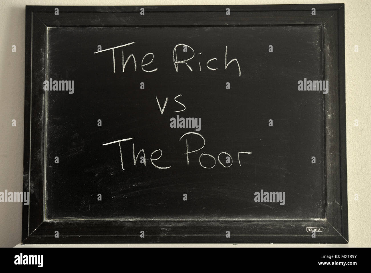 I ricchi vs poveri scritto in bianco gesso su una lavagna. Foto Stock