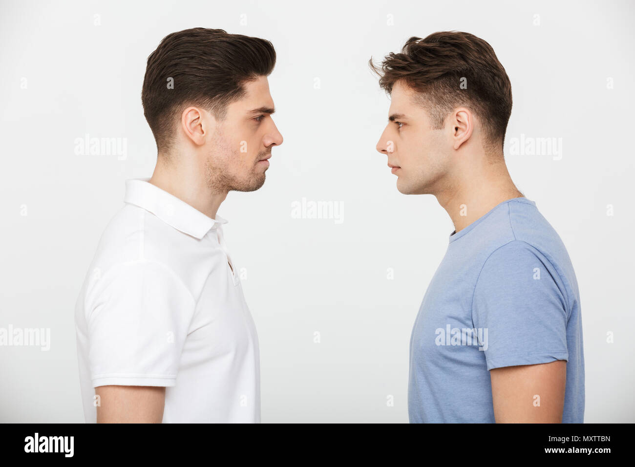 A piena lunghezza ritratto di due giovani arrabbiati uomini guardando ogni altro isolate su sfondo bianco Foto Stock