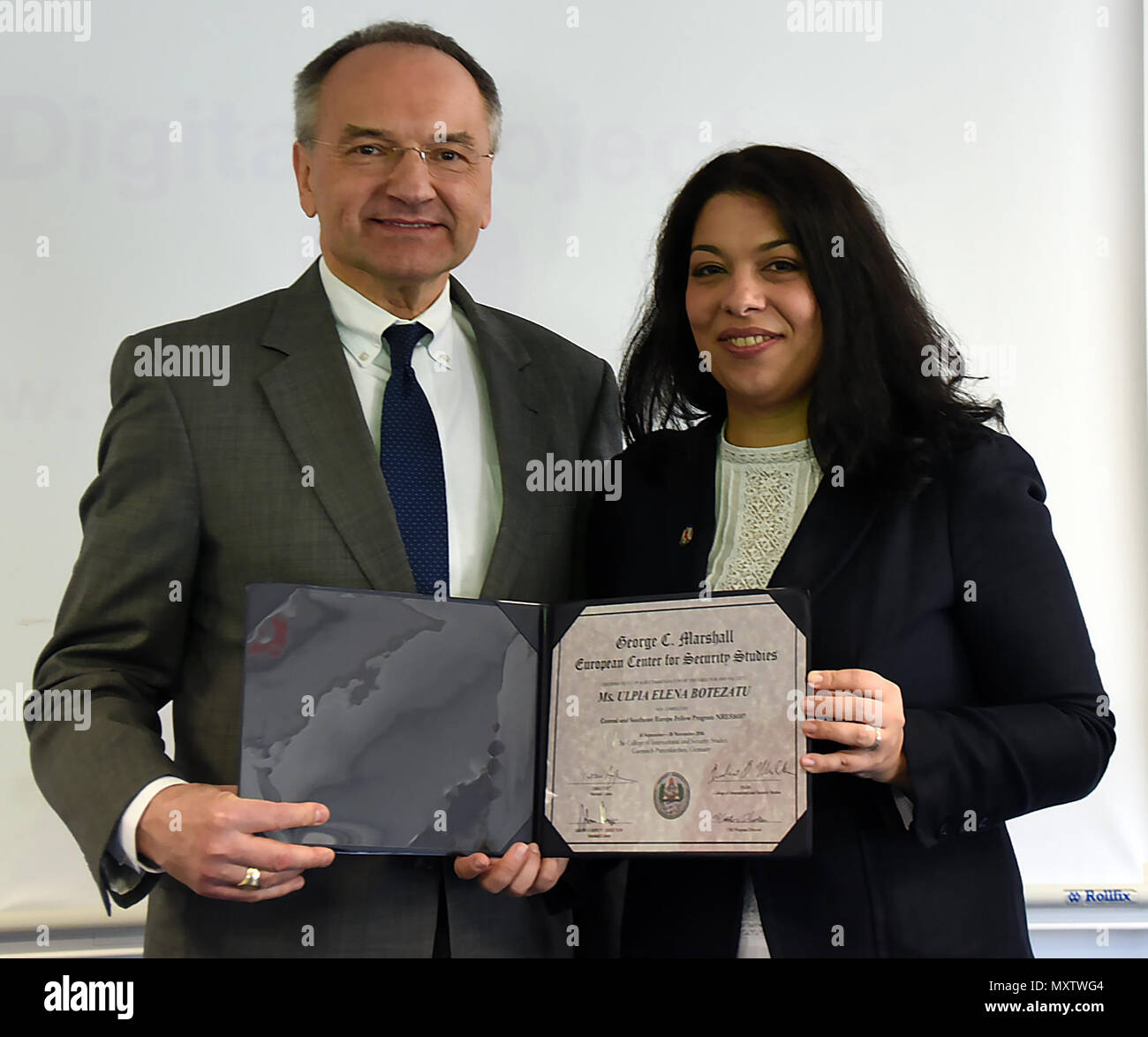 Il dott. Andrea Michta, dean con il Collegio di sicurezza internazionale studi presso la George C. Marshall Centro europeo per gli studi sulla sicurezza, presenta Ulpia Botezatu, un analista con lo spazio delle infrastrutture critiche dipartimento rumeno della Agenzia spaziale con certificato per il completamento del Centro e del sud-est Europa Programma compagni nov. 29. (Marshall Centre Foto di Christine giugno) Foto Stock