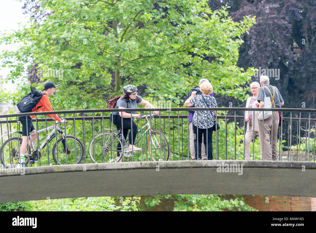 Gli studenti sulle biciclette stop per coppie di pensionati su Garret Hostel lane ponte sopra il fiume Cam, Trinity Hall College, Università di Cambridge, Inghilterra. Foto Stock