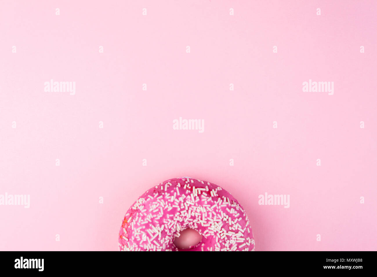 Rosa ciambella smaltata rosa su sfondo color pastello. Lay piatto. Concetto creativo. Foto Stock