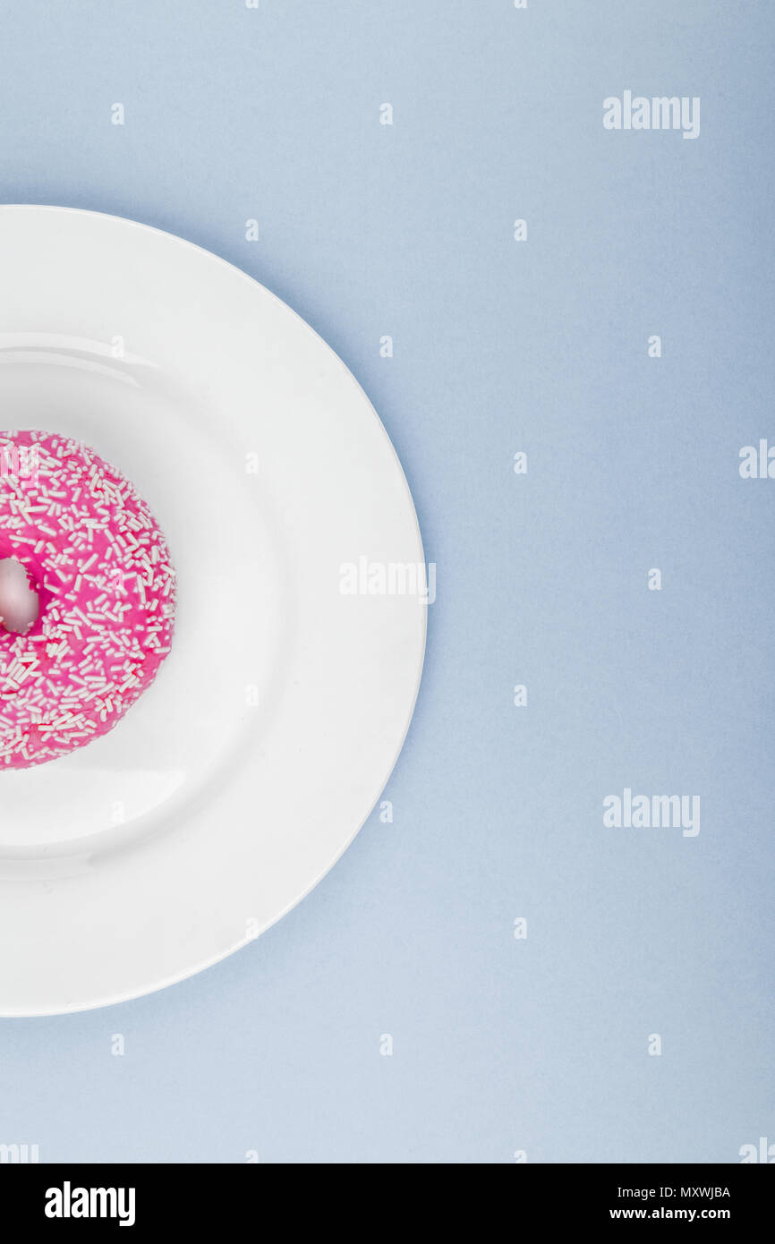 Rosa ciambella smaltata blu su sfondo color pastello. Lay piatto. Concetto creativo. Foto Stock