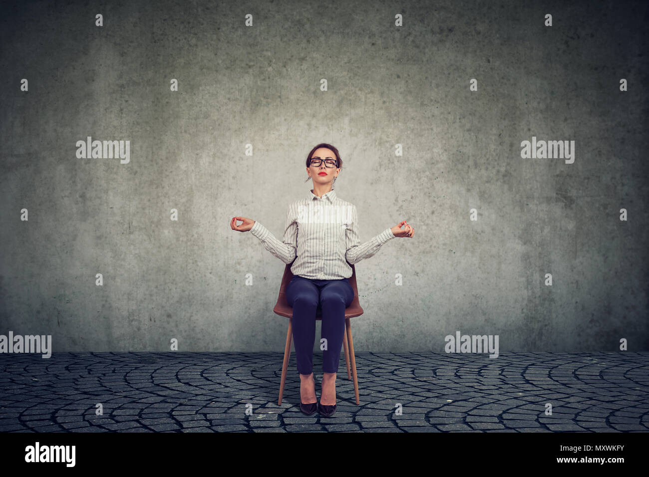 Giovane donna che lavorano seduti su una sedia nella giornata lavorativa e meditare per preservare la pace della mente al lavoro Foto Stock