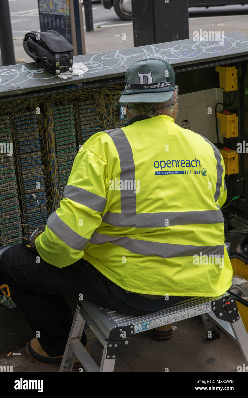 Un BT British Telecom lavoratore della seduta in un aperto armadio delle  telecomunicazioni di effettuare cablaggi e lavori di manutenzione Foto  stock - Alamy