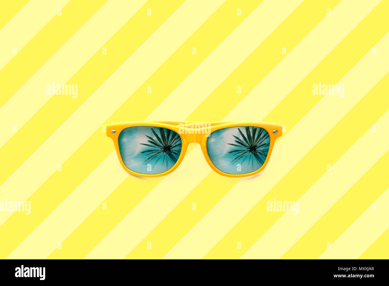 Estate Concetto di immagine: giallo occhiali da sole con Palm tree riflessioni isolato in grandi giallo listati sfondo. Immagine minimalista pronto per l'estate, il sole Foto Stock