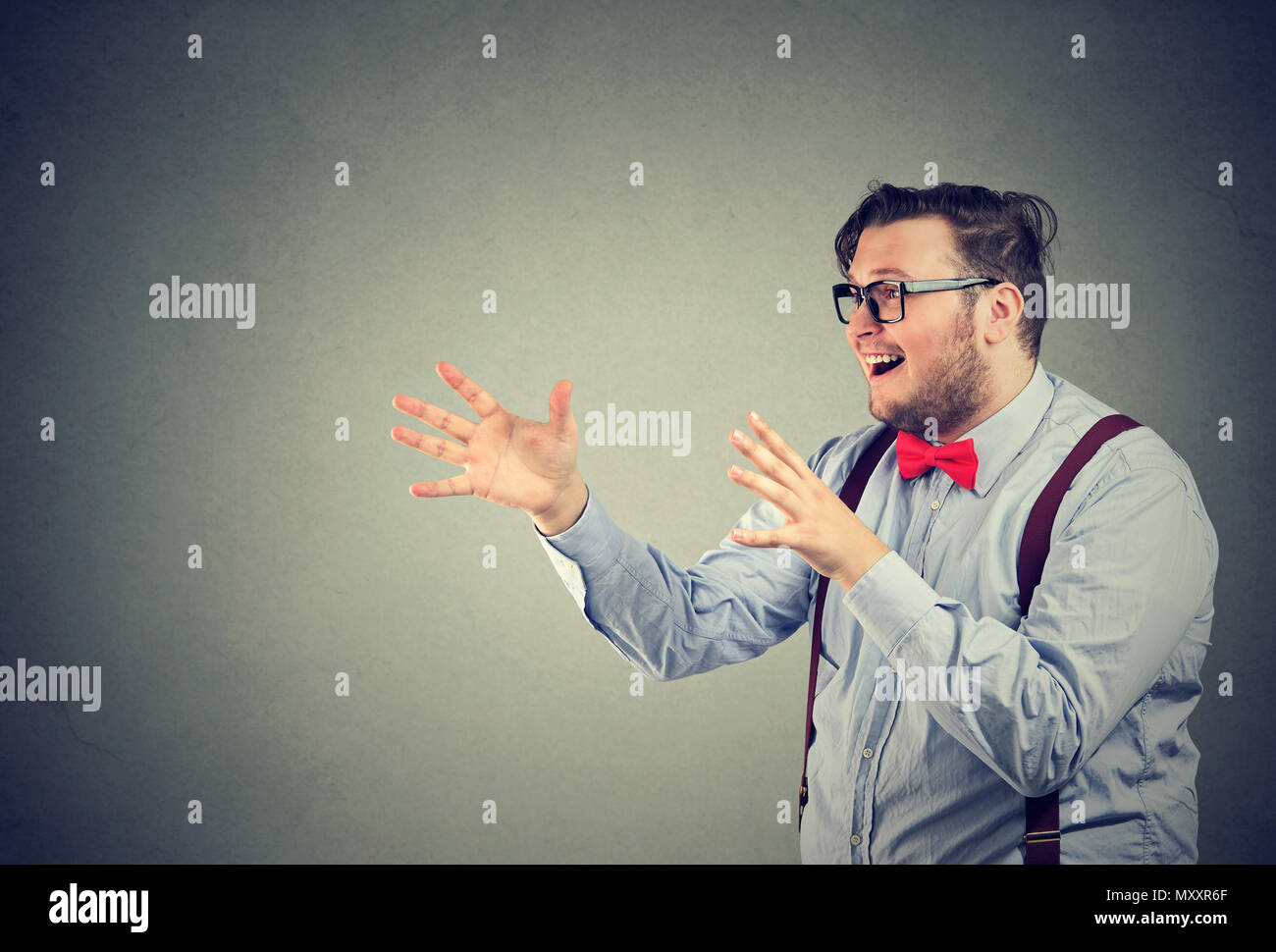 Giovane uomo chunky facendo gesto di caccia cercando di catturare opportunità e vincere la concorrenza Foto Stock